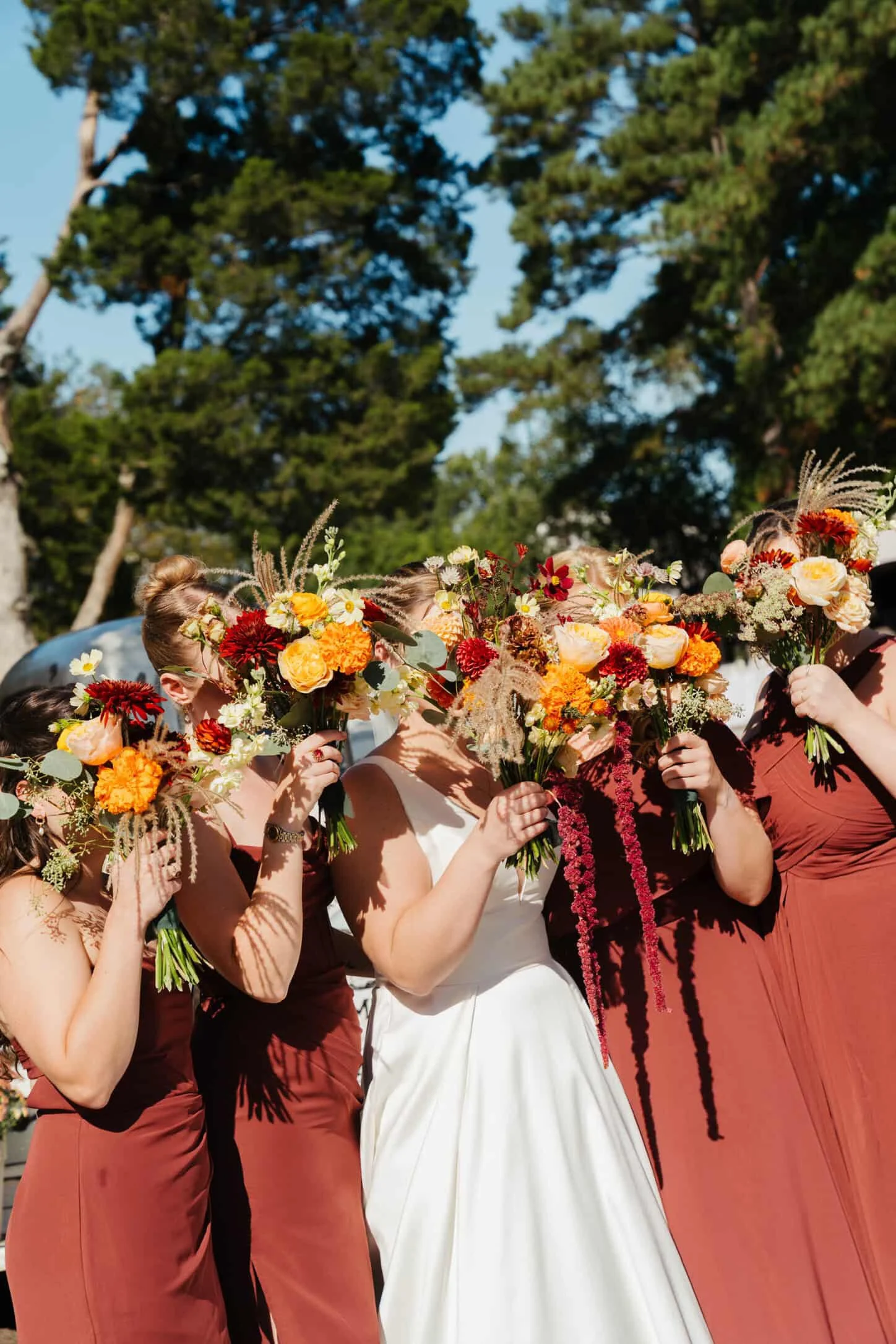 Bridal party holding bouquets up to thier faces
