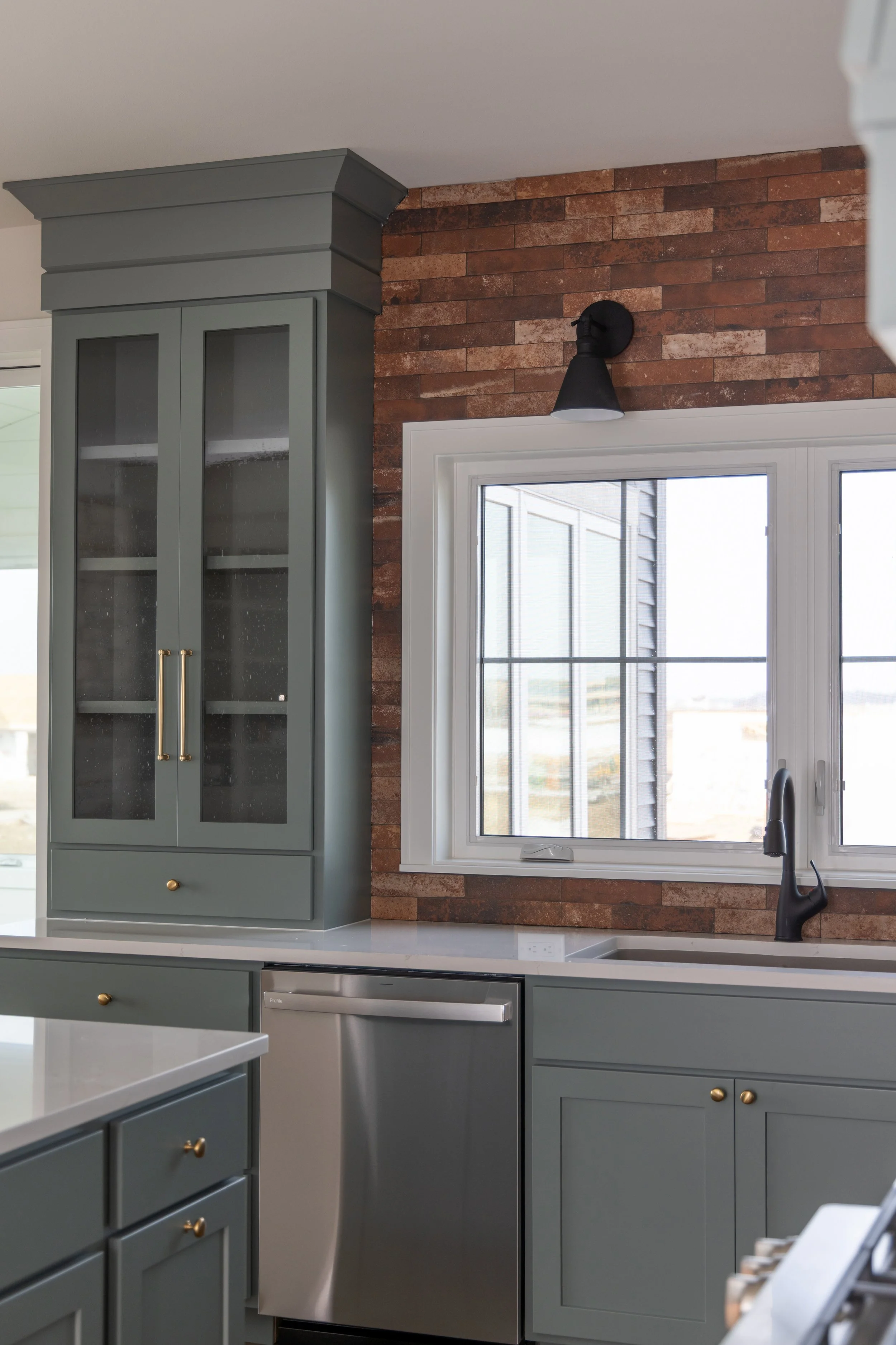 Blue kitchen cabinets with a brick tile and white window in a kitchen