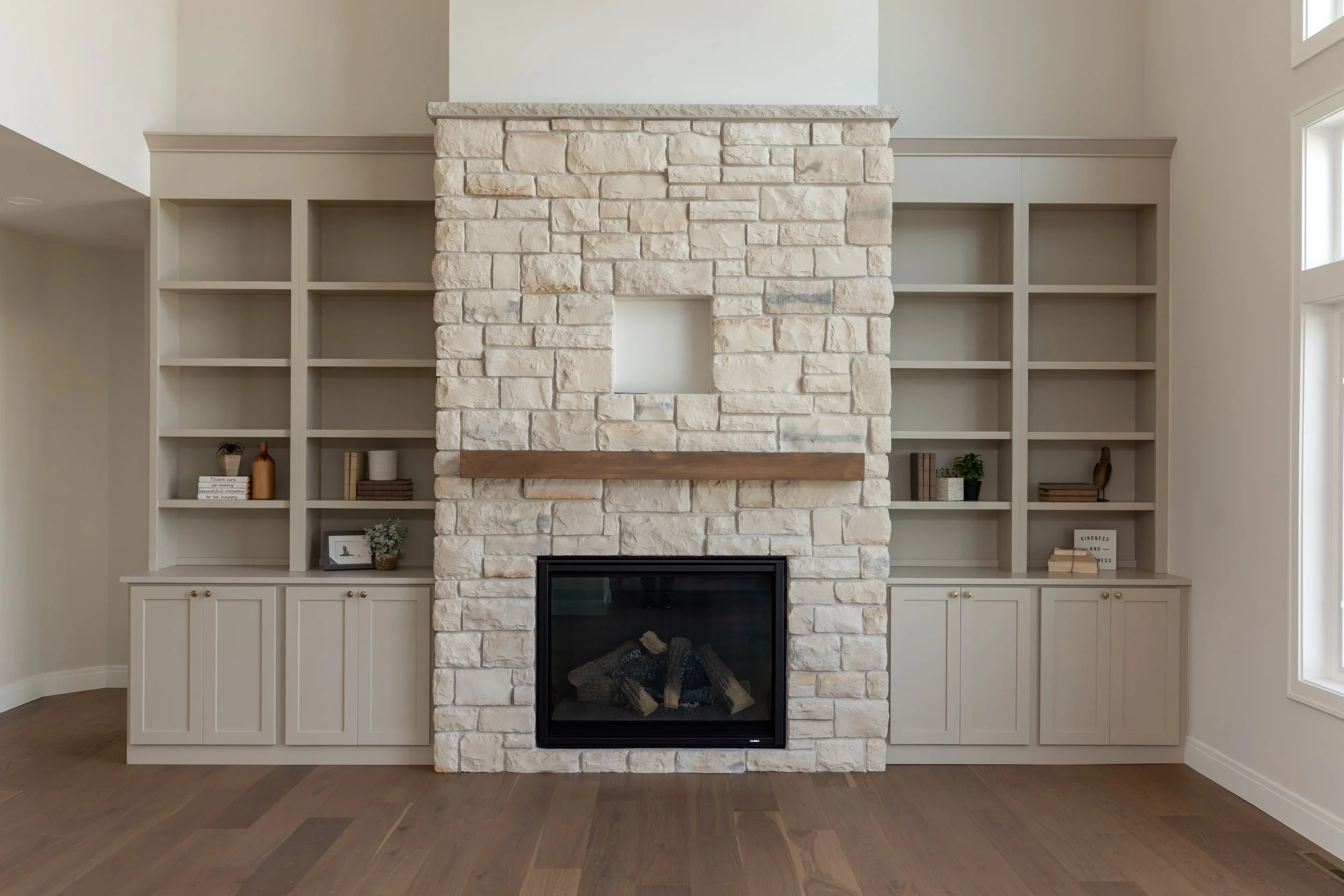 Light bricked fireplace flanked by wooden light colored built in shelves