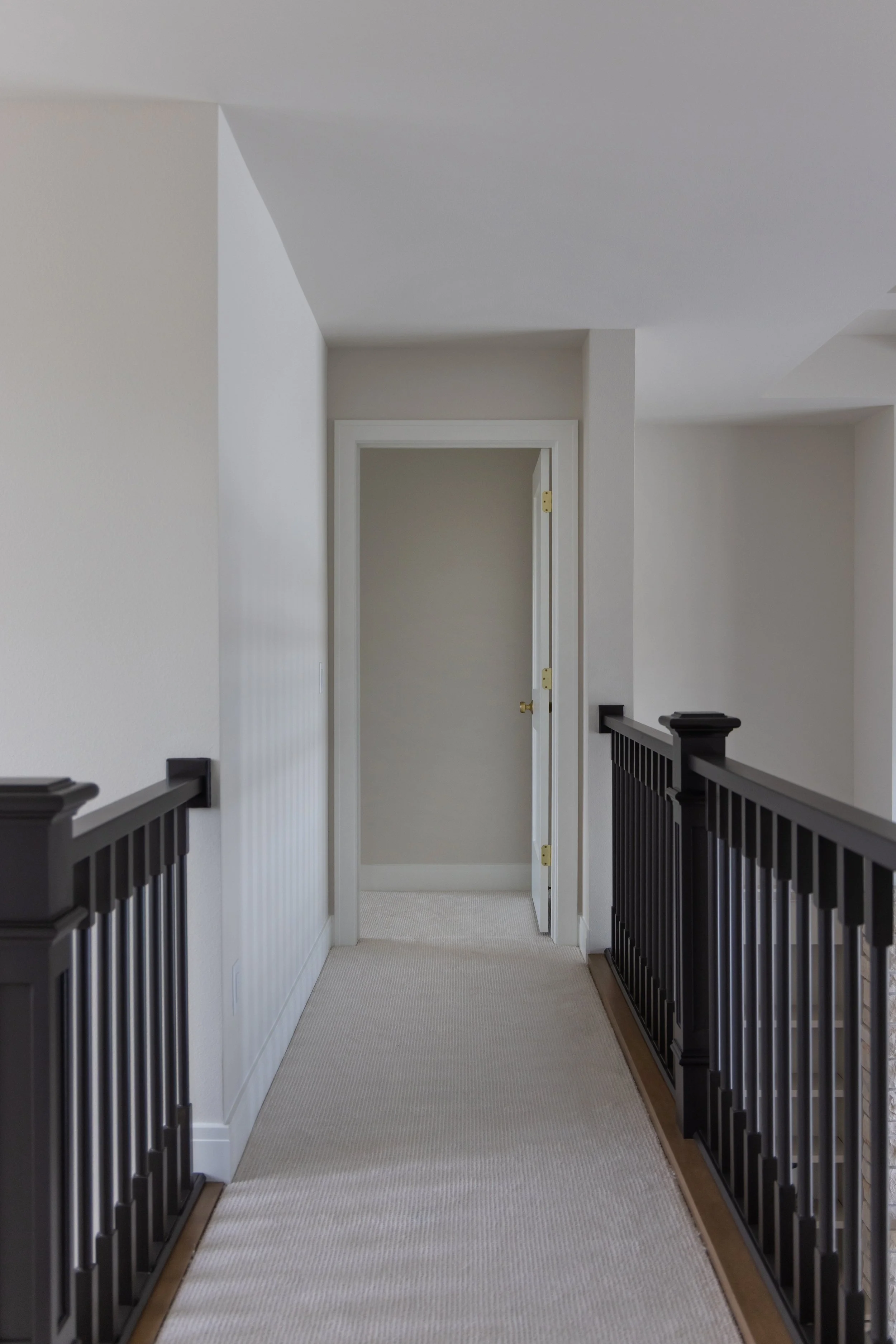 White hallway with black stair railing