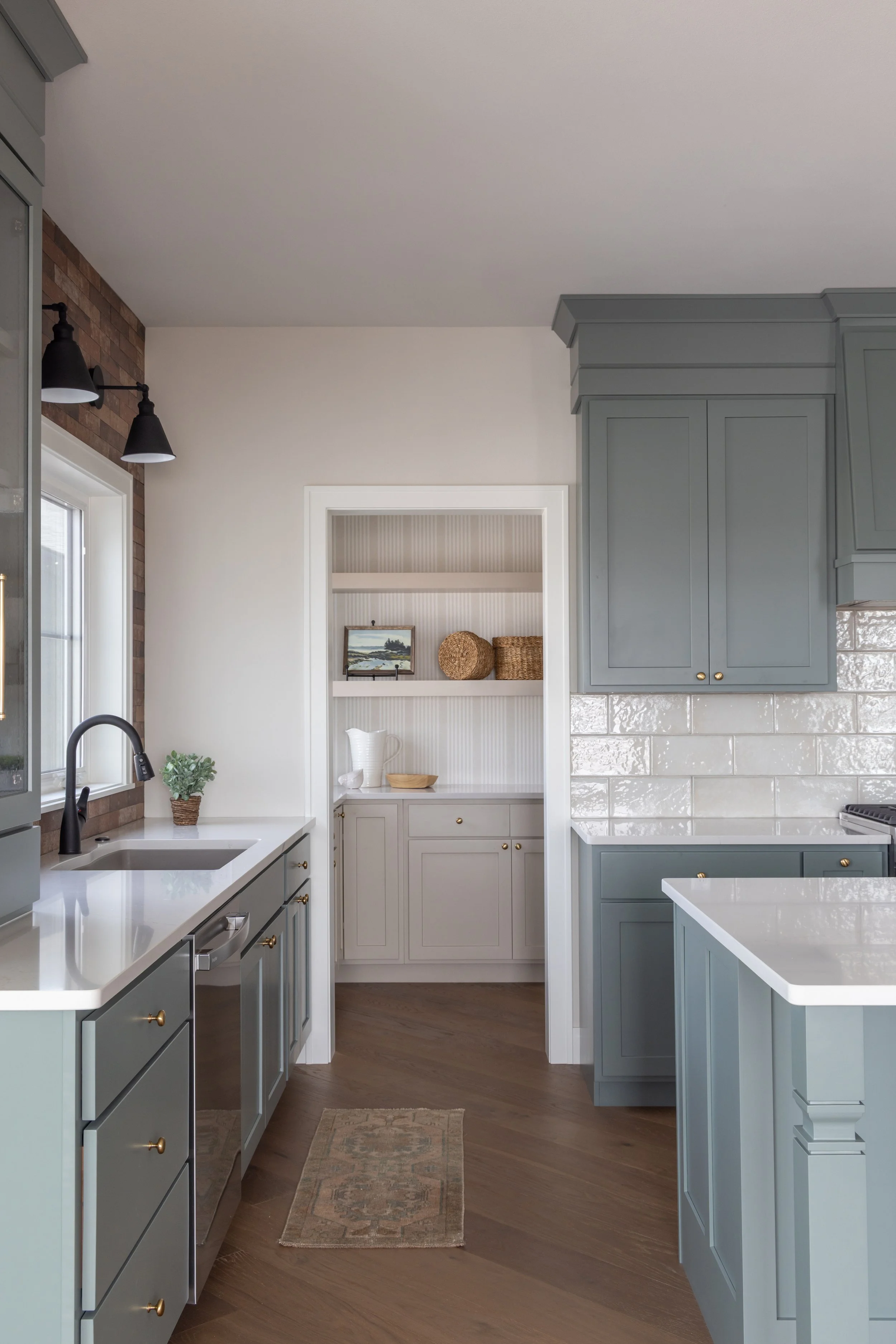 Blue kitchen cabinets and white subway tile with a view to an open pantry