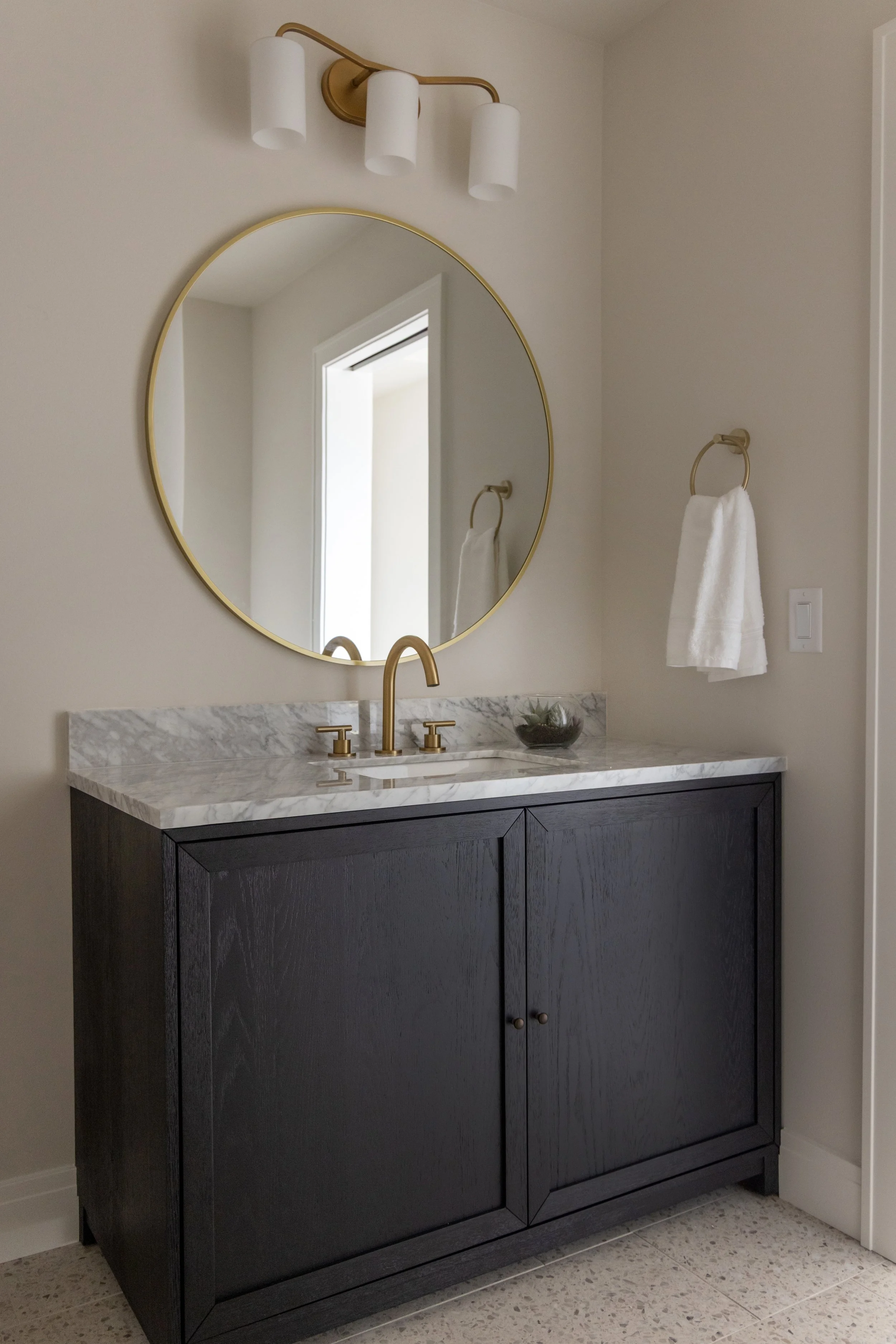 Black bathroom vanity with a large circle mirror