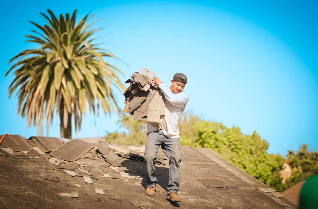GreenCal team member carrying materials on a roofing job