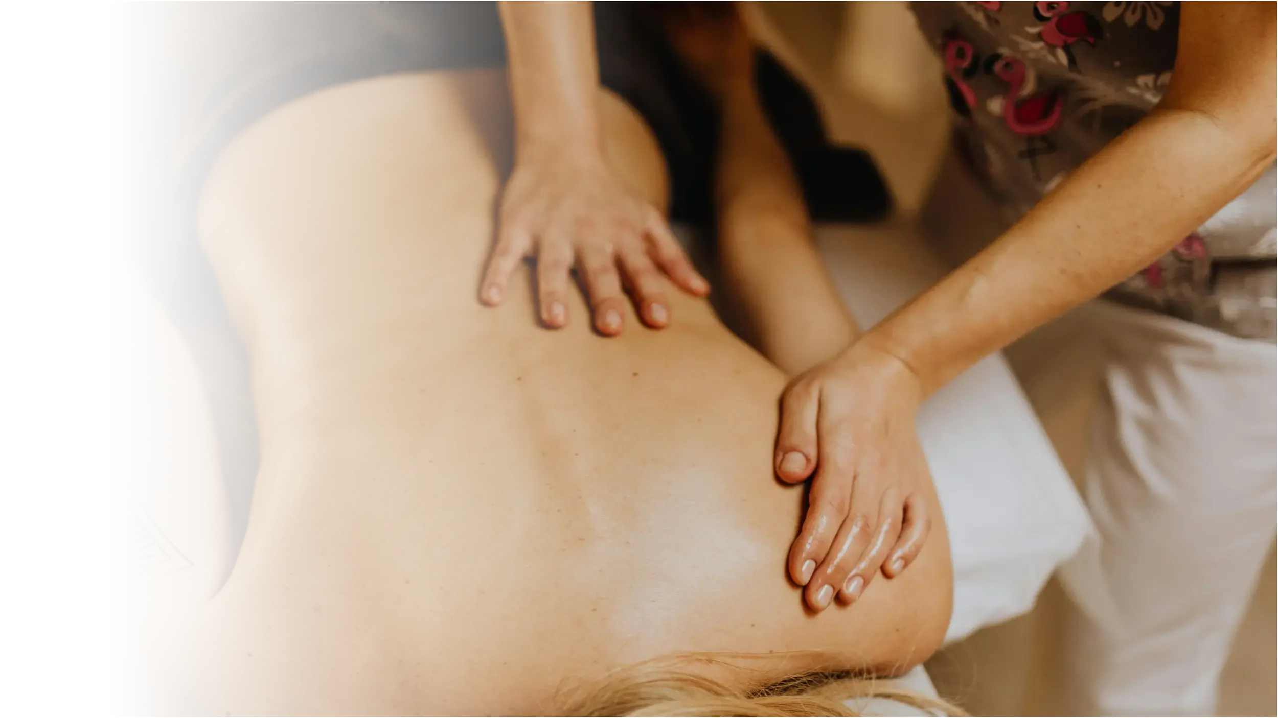 Person receiving a massage, lying face down with hands on their back, in a massage therapy session.