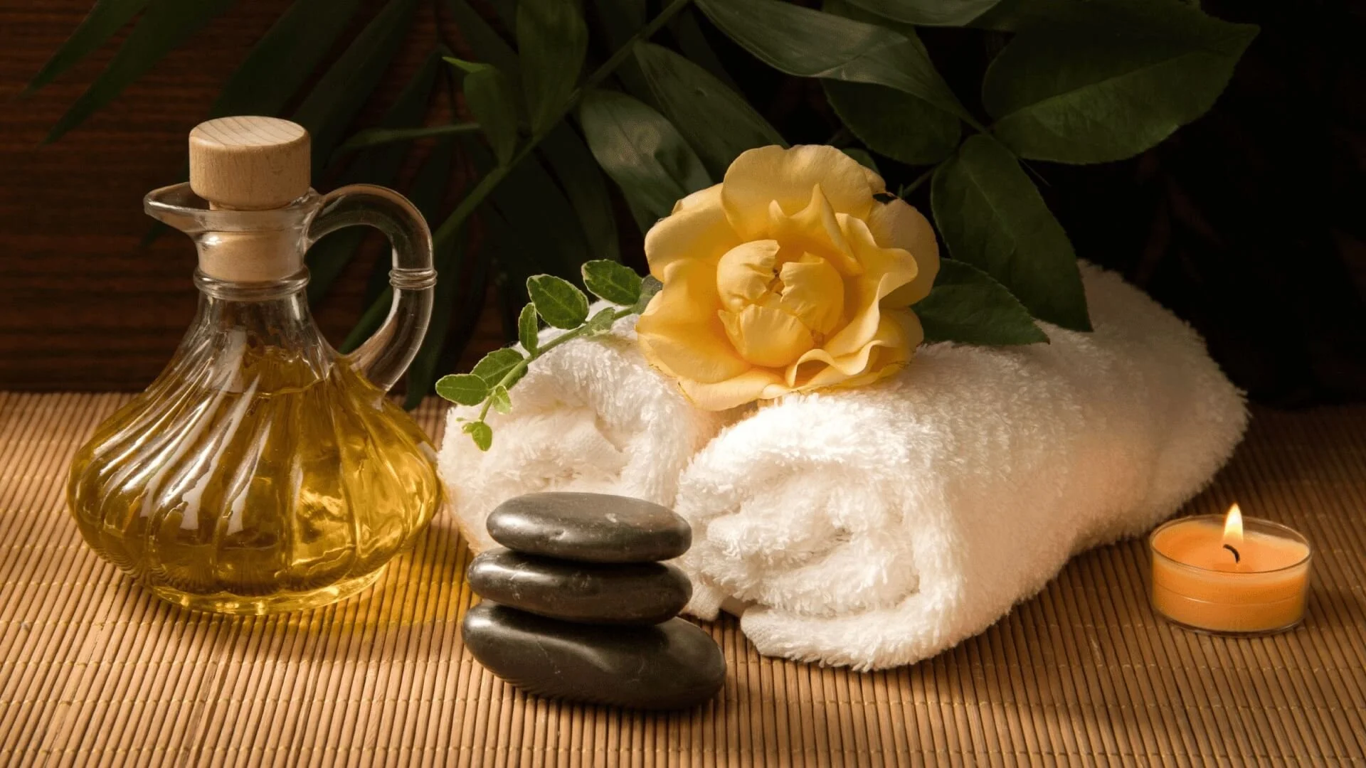 Massage therapy services at Selina’s Therapy Center in Pacific Grove – relaxing spa setting with oil, towels, stones, and candle.