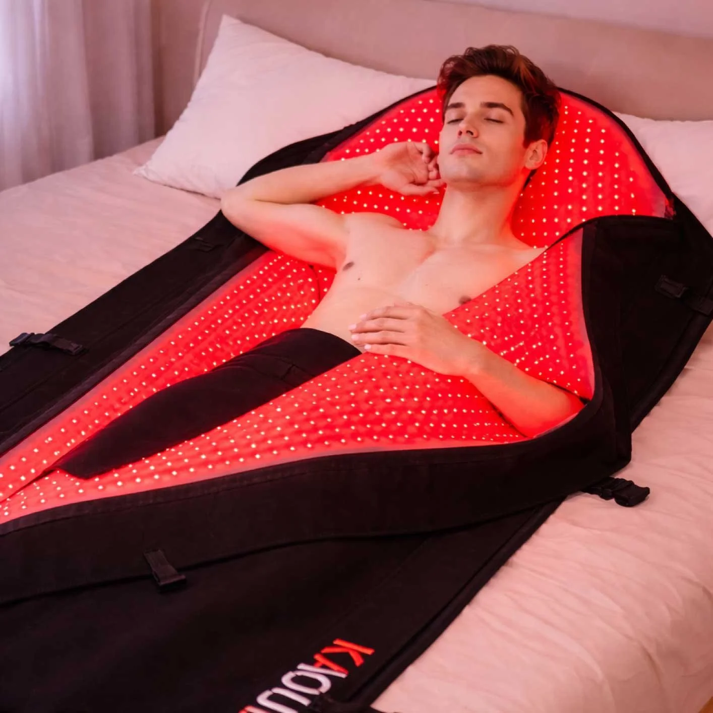 Man relaxing on a full-body red light therapy panel emitting red and near-infrared light for whole-body recovery and wellness.