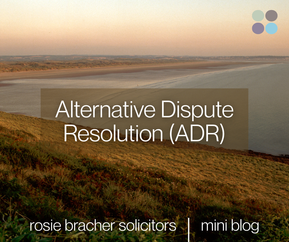 Sunset over a coastal landscape with grassy hills and a calm body of water