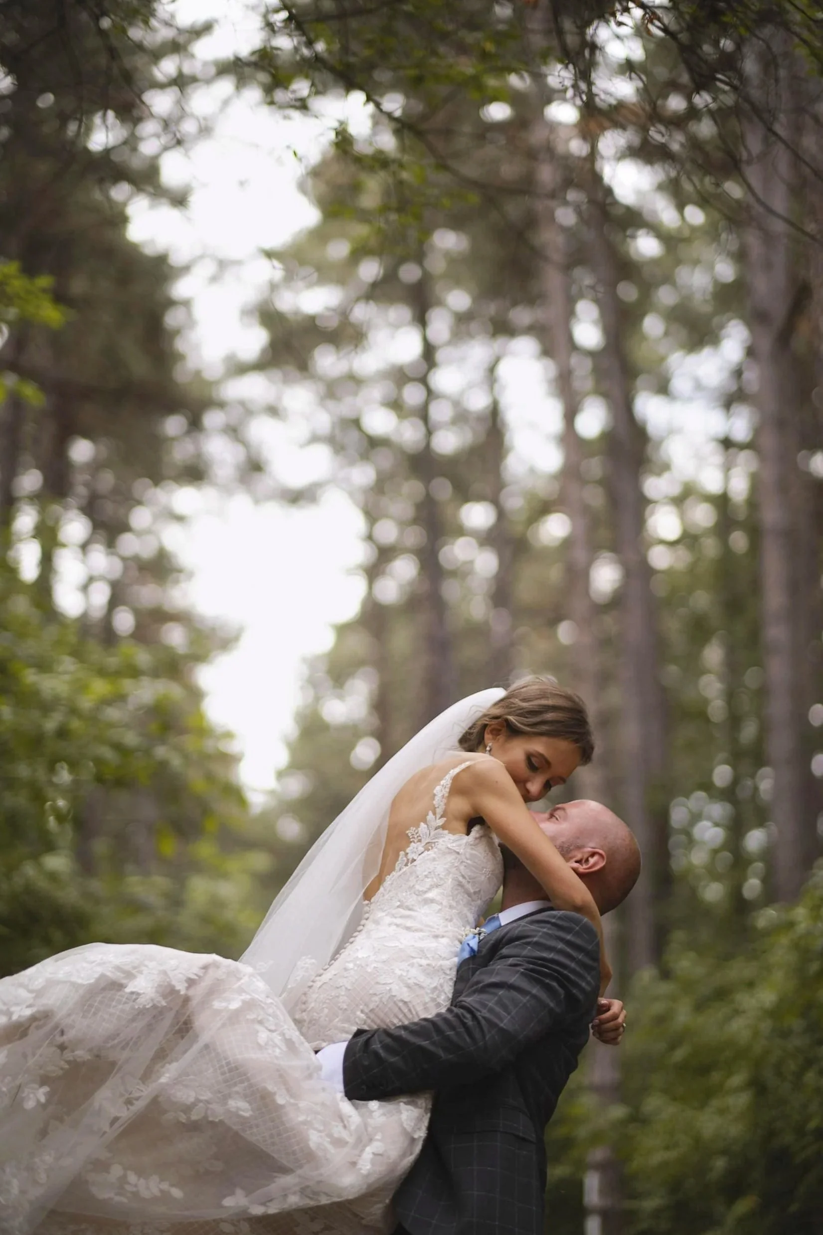 Танцуващи булка и младоженец на фона на зелена гора.