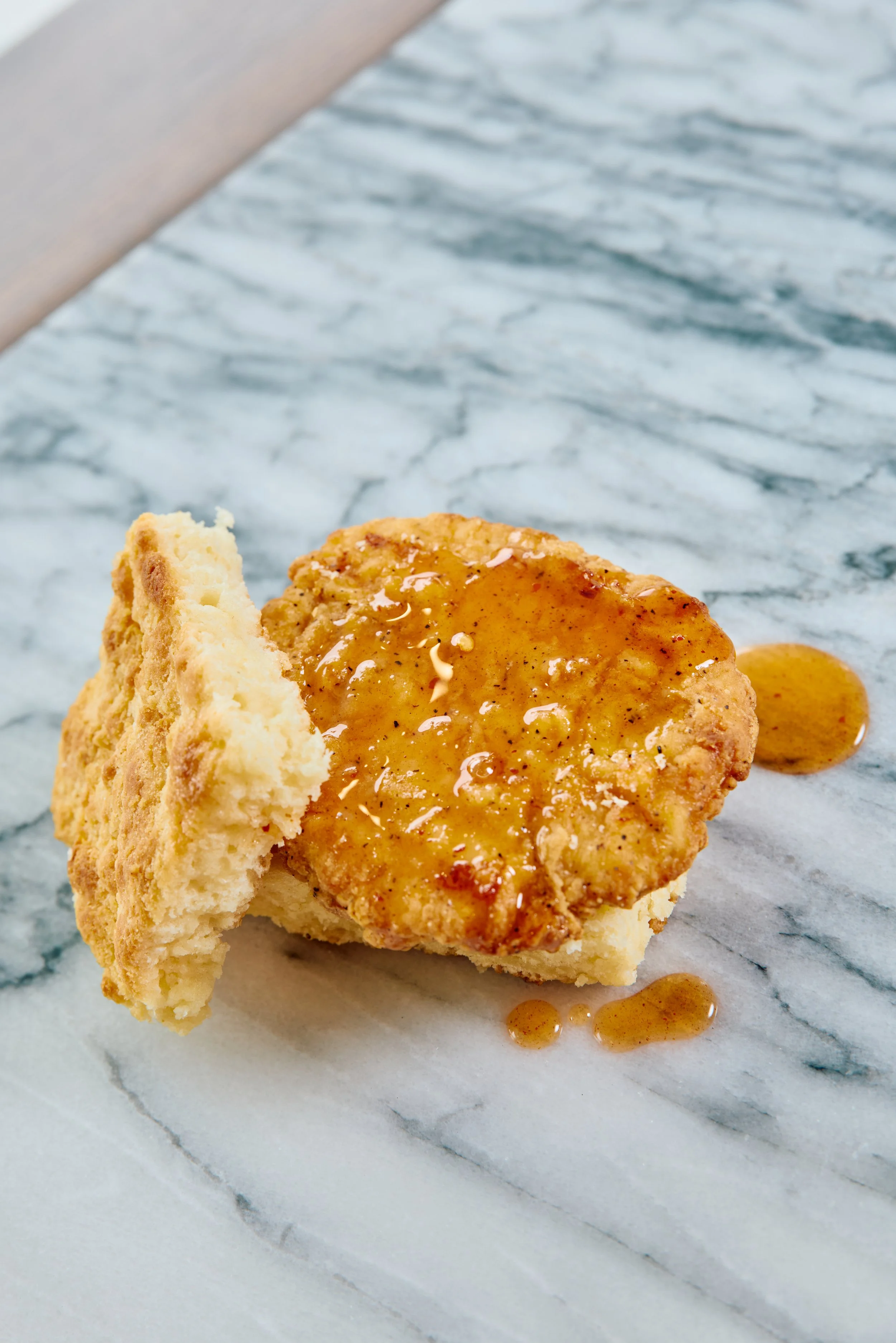 A biscuit topped with breaded chicken and peach hot honey.