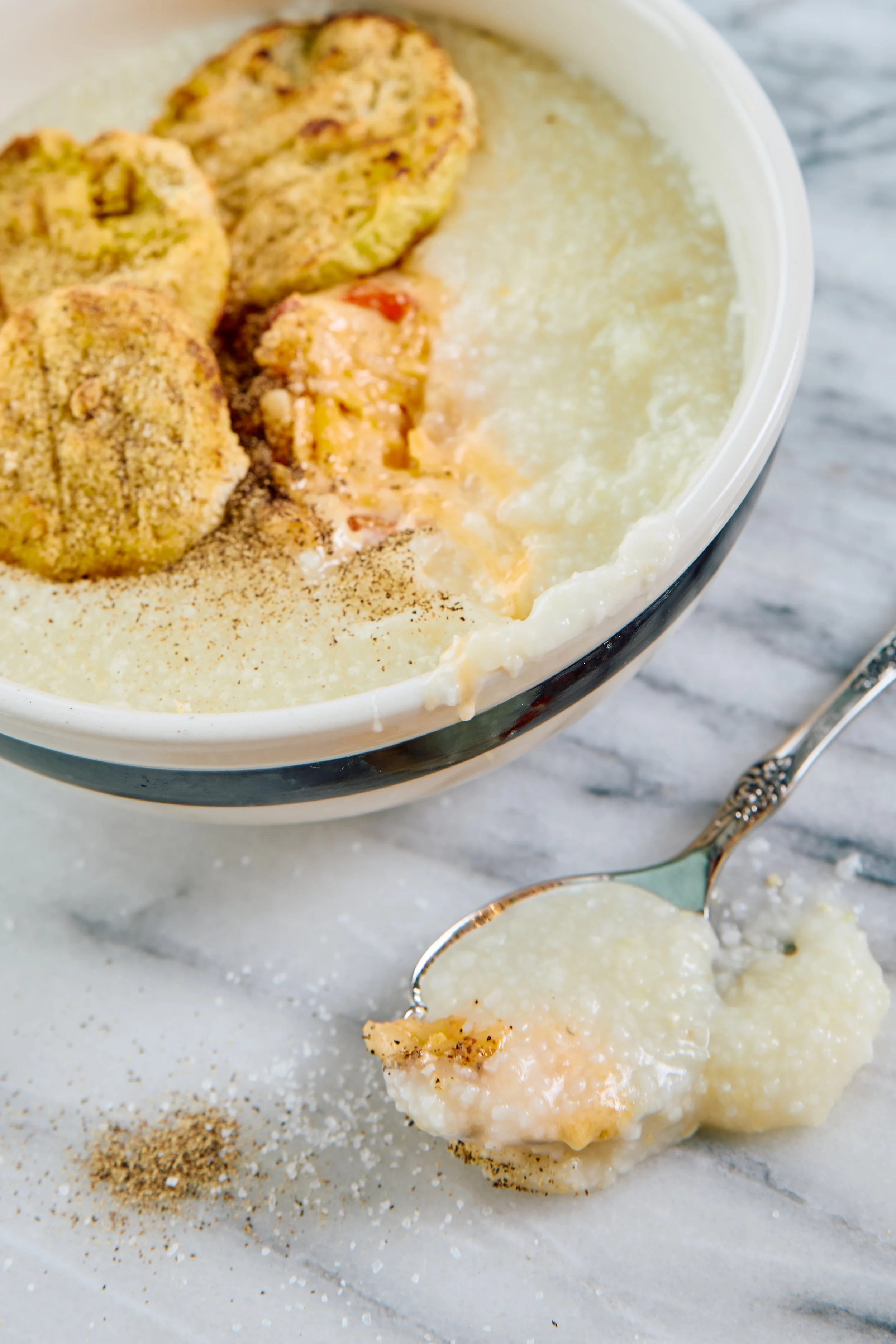 A bowl of creamy grits topped with pimiento cheese and fried green tomatoes.