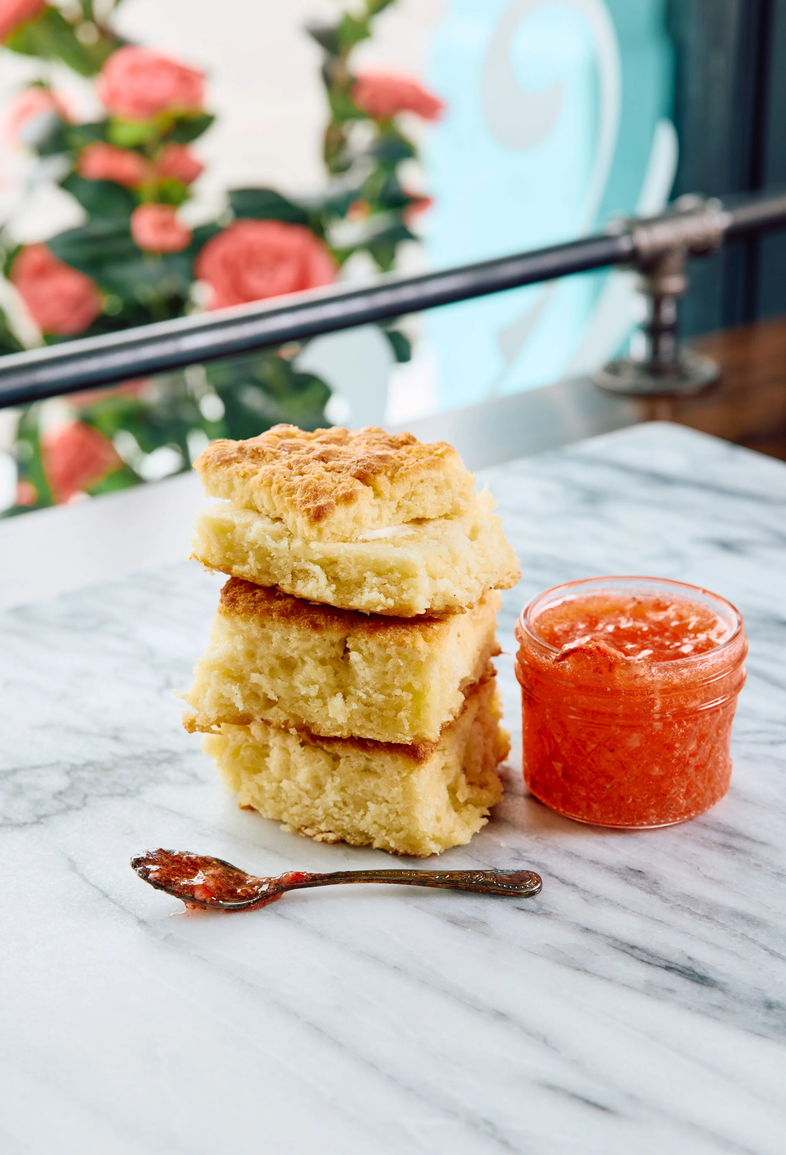 Four biscuits stacked, with a jar of strawberry jam.