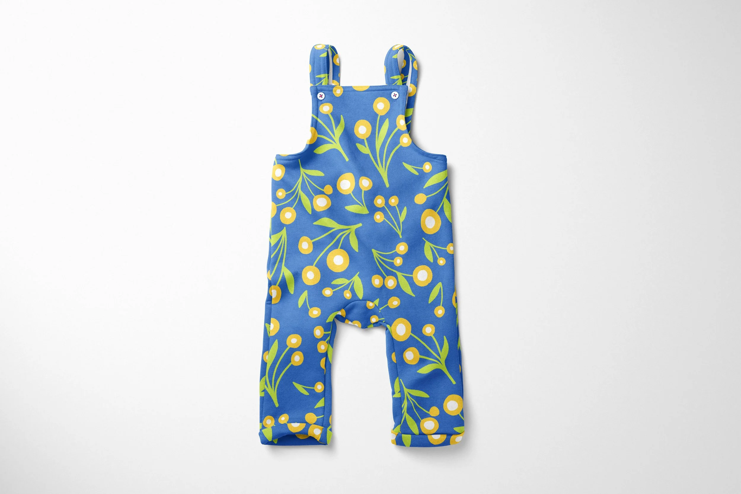 blue children's overalls featuring a cheerful chamomile floral pattern. The fabric has a bright blue background scattered with stylized white and yellow chamomile flowers on delicate green stems. The overalls feature adjustable straps with white butt