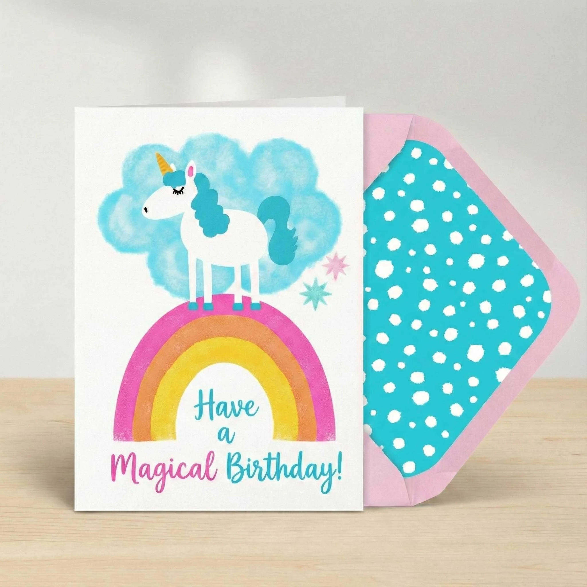 Colorful birthday card with a unicorn and rainbow, reading 'Have a Magical Birthday!', with a pink and blue dotted envelope.