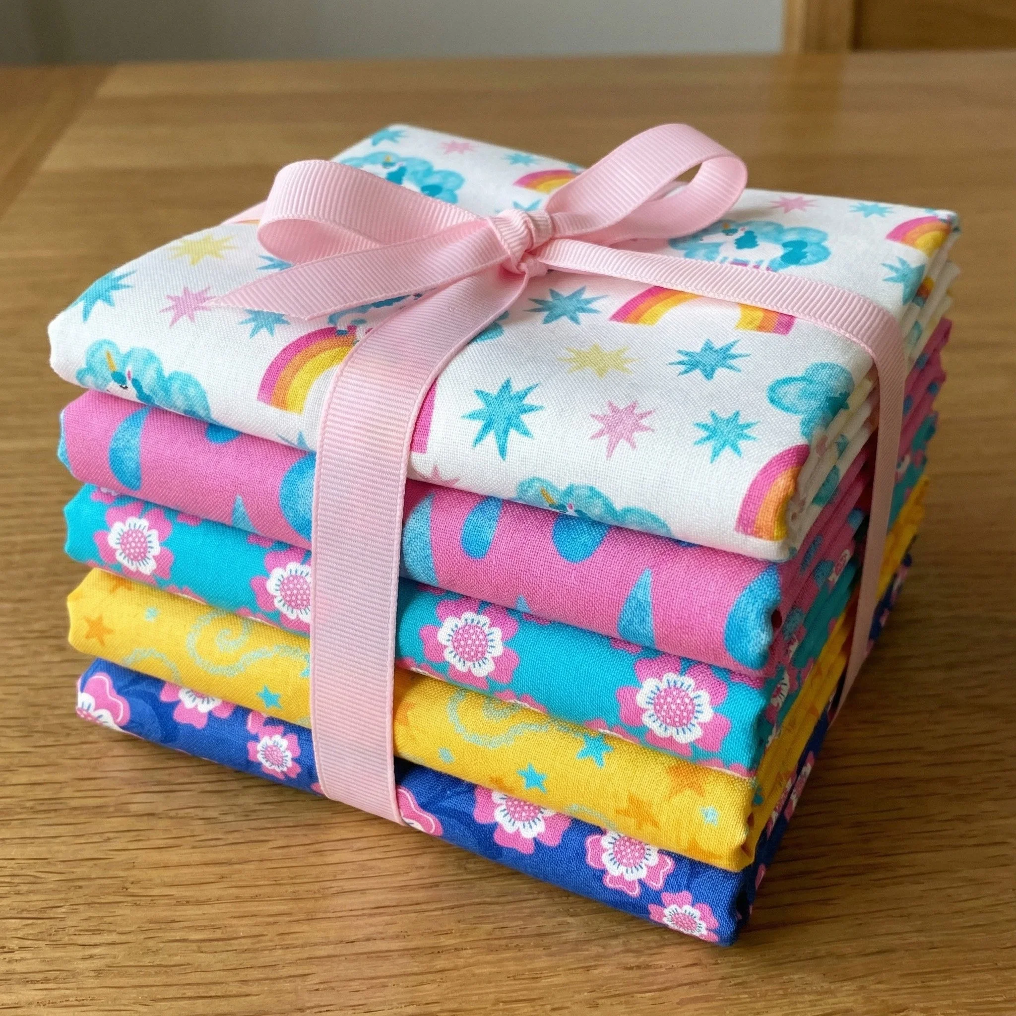 Stack of colorful unicorn and rainbow fabric prints tied with pink ribbon
