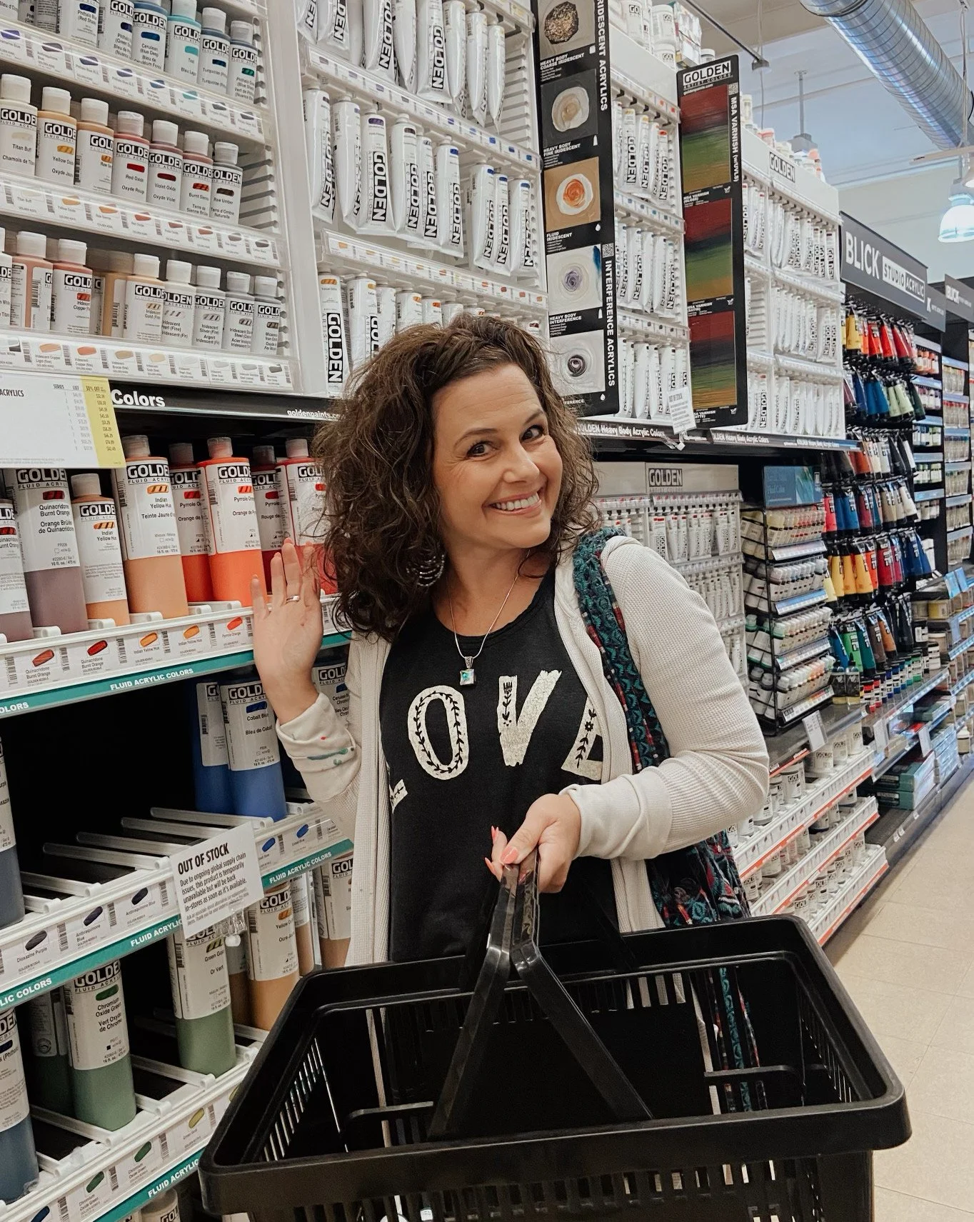 Stephanie Ignazio shopping in an art supply store surrounded by rows of paint in all colors of the rainbow.