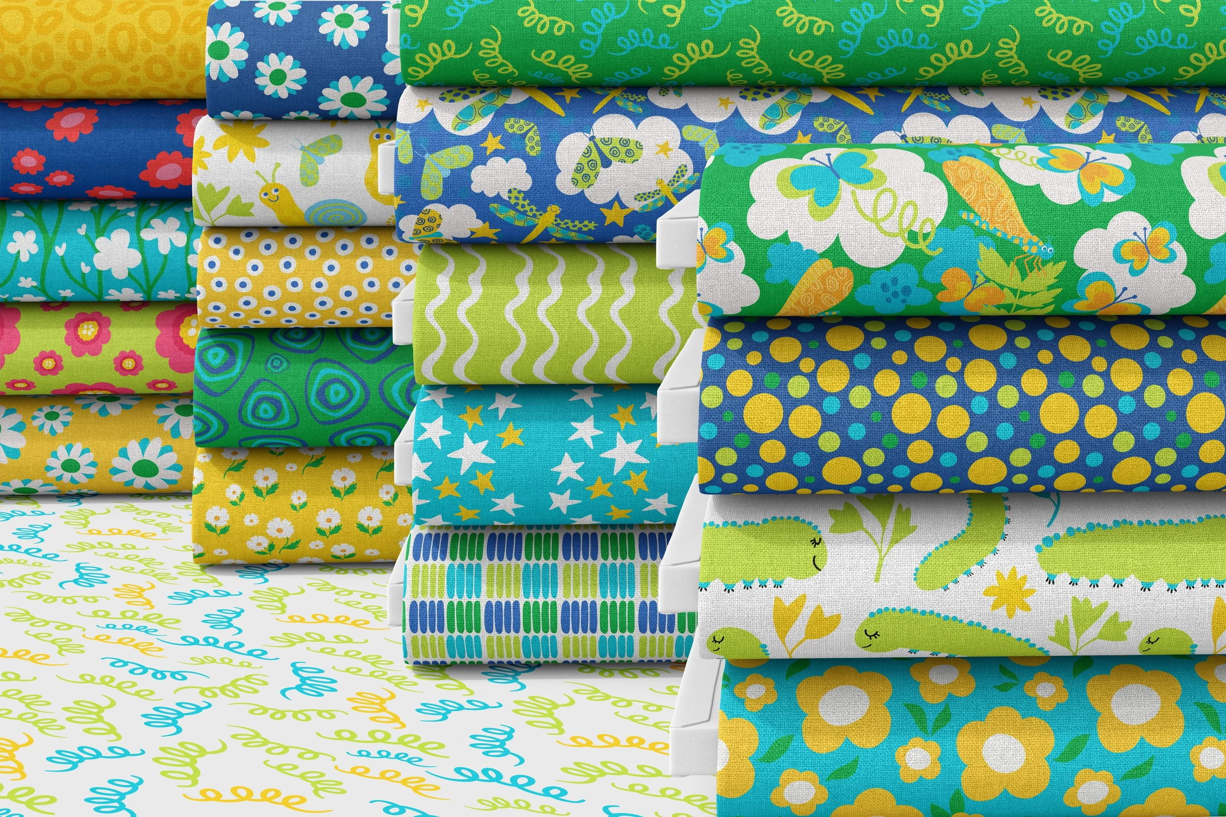 Fabric bolts displaying the Bugs and Blooms pattern collection, featuring playful insects, flowers, caterpillars, butterflies, stars, dots, and coordinating geometric designs in bright, cheerful colors. A versatile surface pattern collection designed