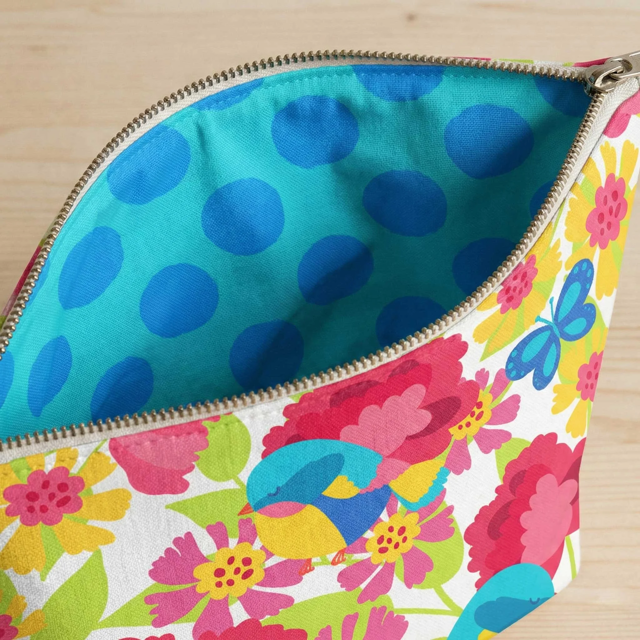 zippered makeup bag with colorful bird design as exterior pattern with large aqua polka dot lining