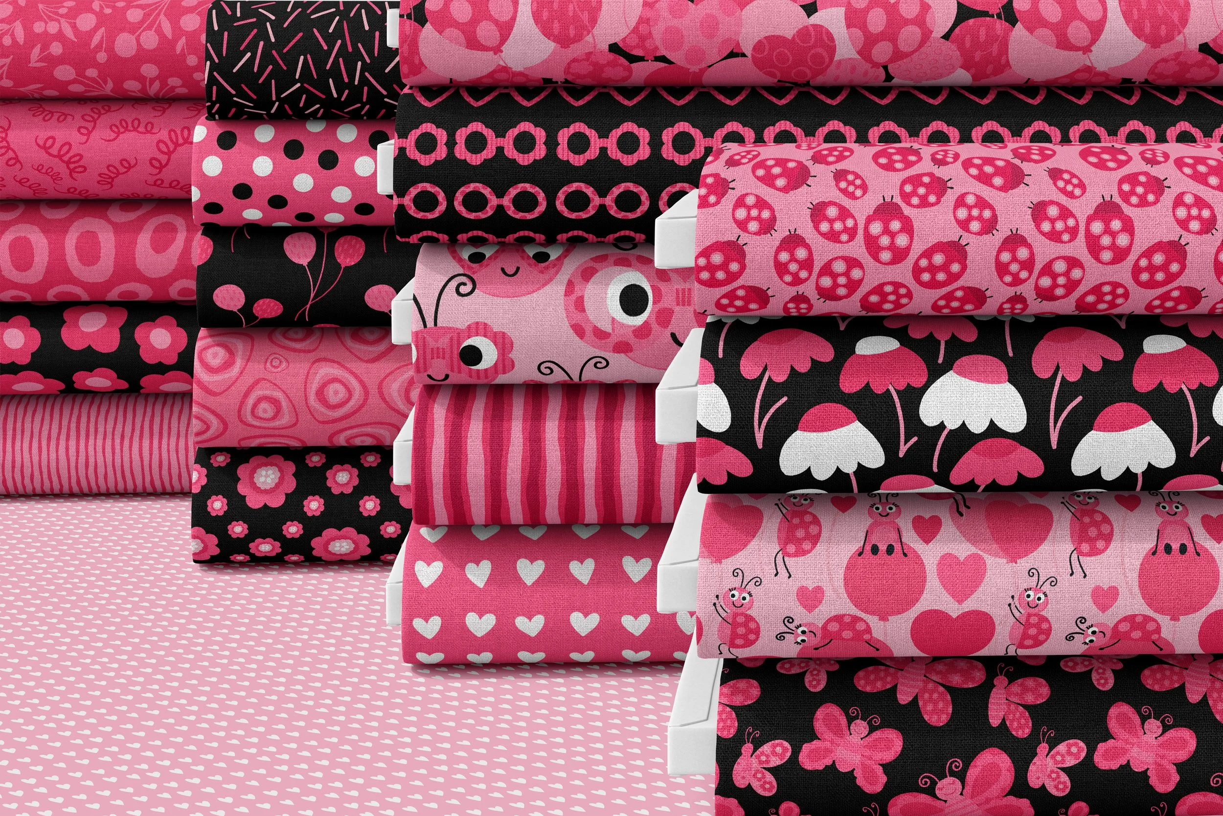 Fabric bolts displaying the full extended Love and Ladybugs collection, featuring whimsical ladybug characters, butterflies, hearts, florals, stripes, and coordinating blender patterns. A cohesive surface pattern collection designed for children’s ap
