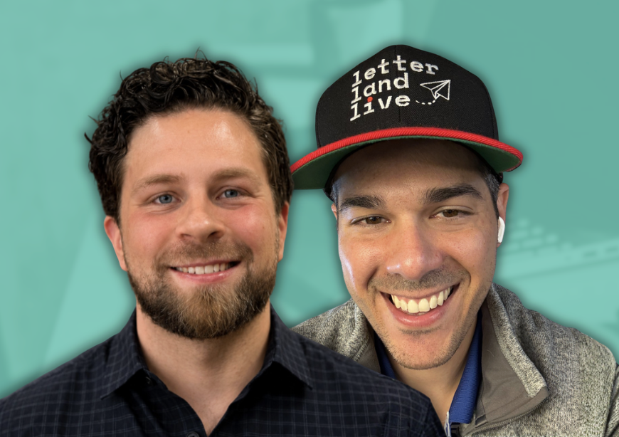 Two smiling men taking a selfie, one with a beard and another wearing a black cap with red trim and the words 'letter land live' and a paper airplane graphic.