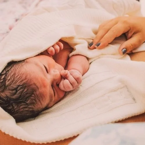 newborn baby cuddled in mothers arms