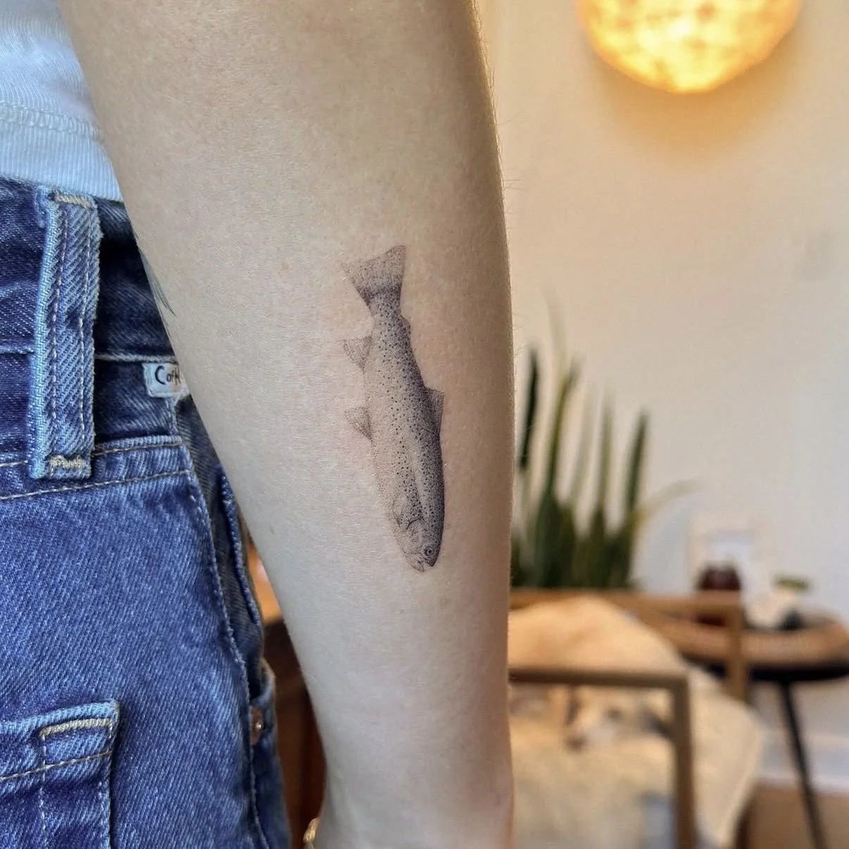 Tattoo of a realistic fish on a person's inner forearm