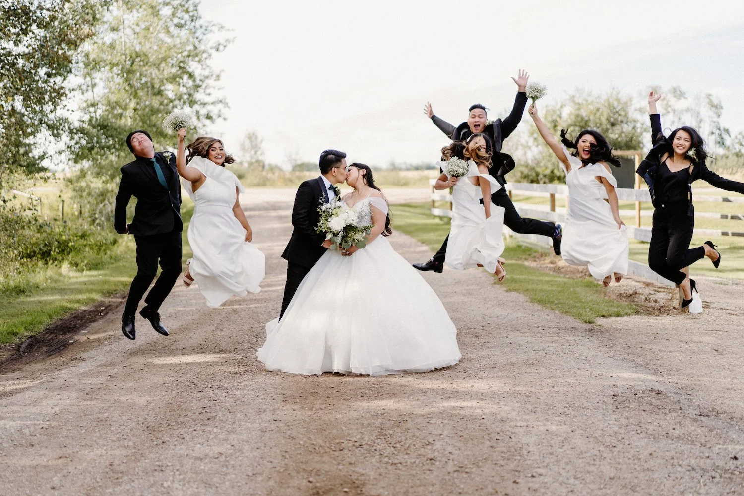Bride and groom with wedding party celebrating on a country road at a destination wedding venue near Edmonton and Calgary, Alberta