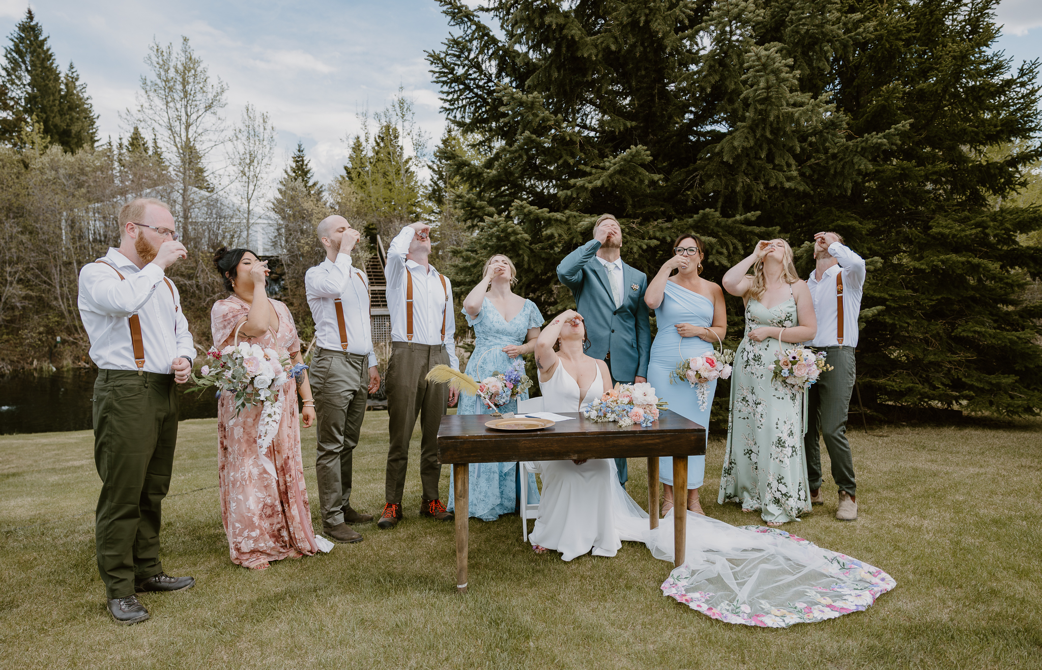 Bride and wedding party celebrating together outdoors at Pine and Pond wedding venue in Alberta