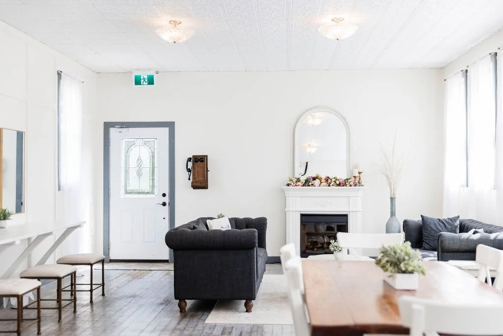 Spacious bridal cottage interior at Pine and Pond featuring a cozy lounge area, white fireplace mantel, and natural light — an inviting setting for bridesmaids and family on the wedding morning.