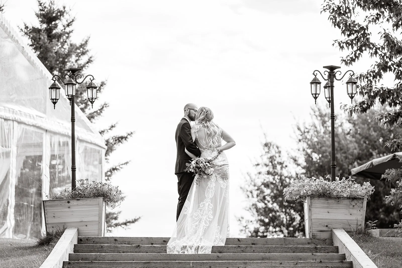 Bride and groom standing on steps near a clear tent at a destination wedding venue near Edmonton and Calgary, Alberta