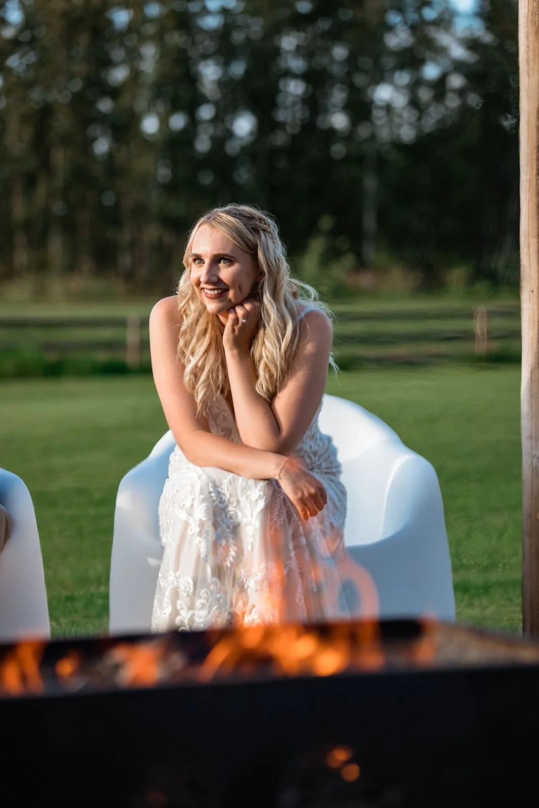 Bride relaxing beside the outdoor fire pit at Pine and Pond Wedding Venue