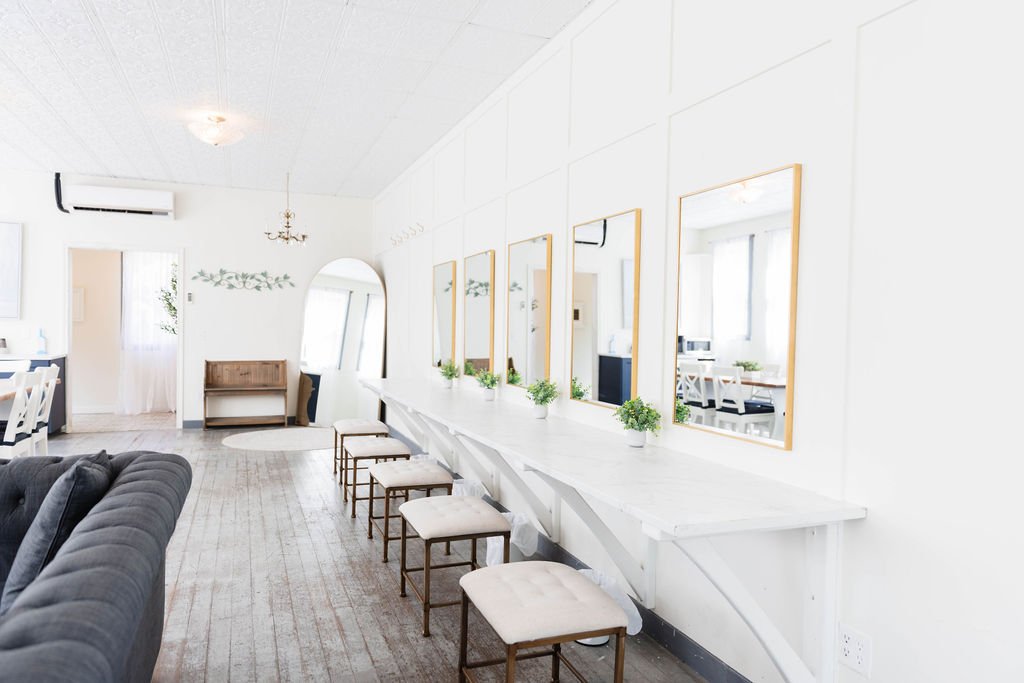 Full view of Pine and Pond’s bridal getting-ready suite showcasing a spacious layout, makeup counters, elegant mirrors, lounge seating, and rustic white interior — a serene place for wedding morning preparations.