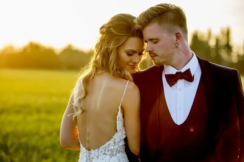 Bride and groom at sunset in a field