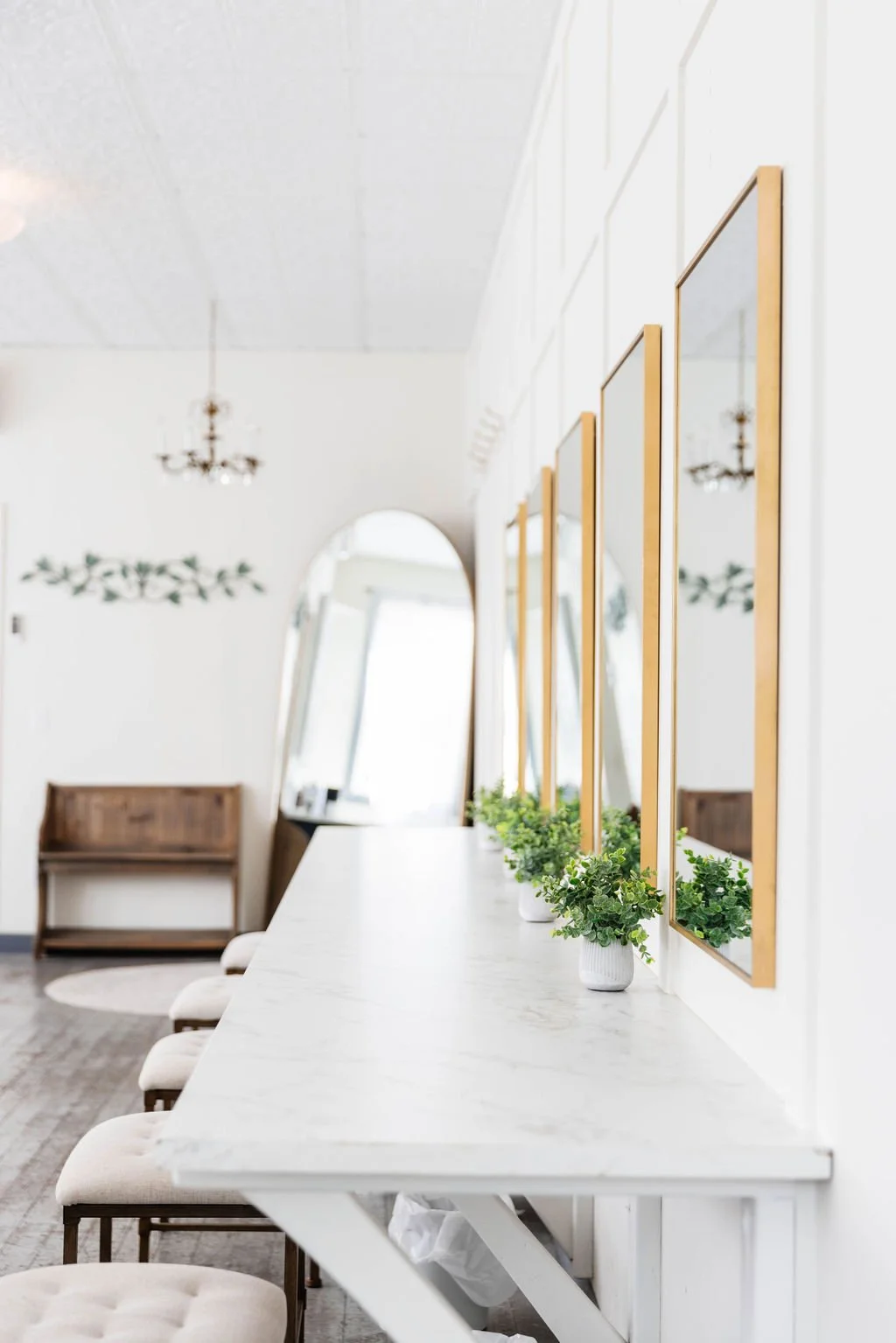 Bright, elegant bridal getting-ready room at Pine and Pond Wedding Venue featuring a long white makeup counter with gold-framed mirrors, plush stools, and natural light — a perfect space for brides and bridesmaids to prepare on the wedding morning in