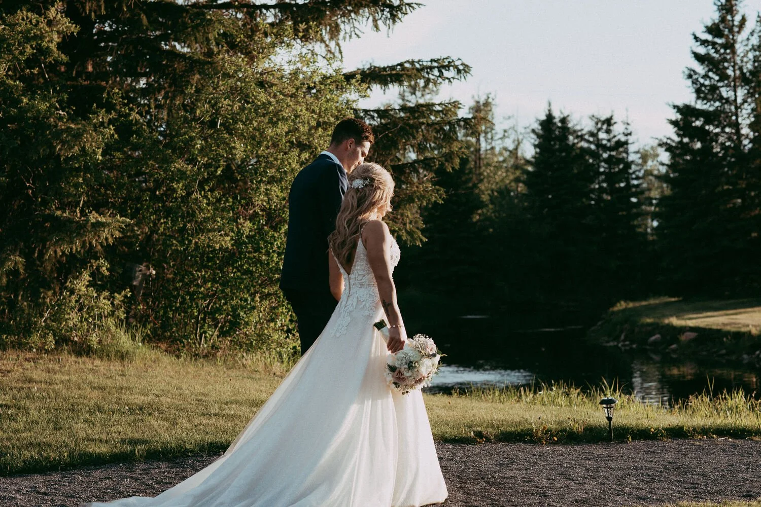 Bride and groom walking together at golden hour beside the pond at Pine and Pond Wedding Venue