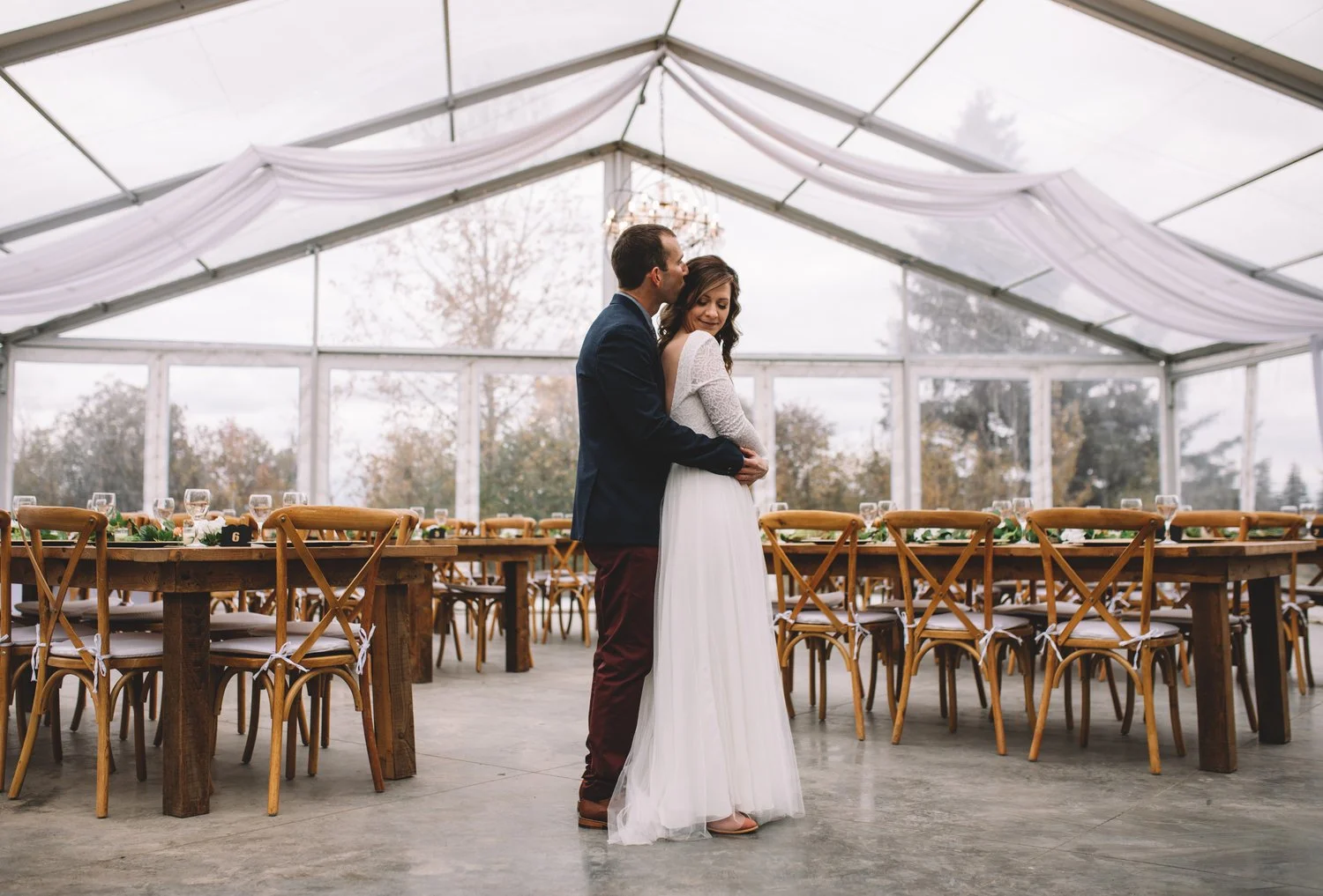 Bride and groom embracing inside the clear tent wedding reception at Pine and Pond