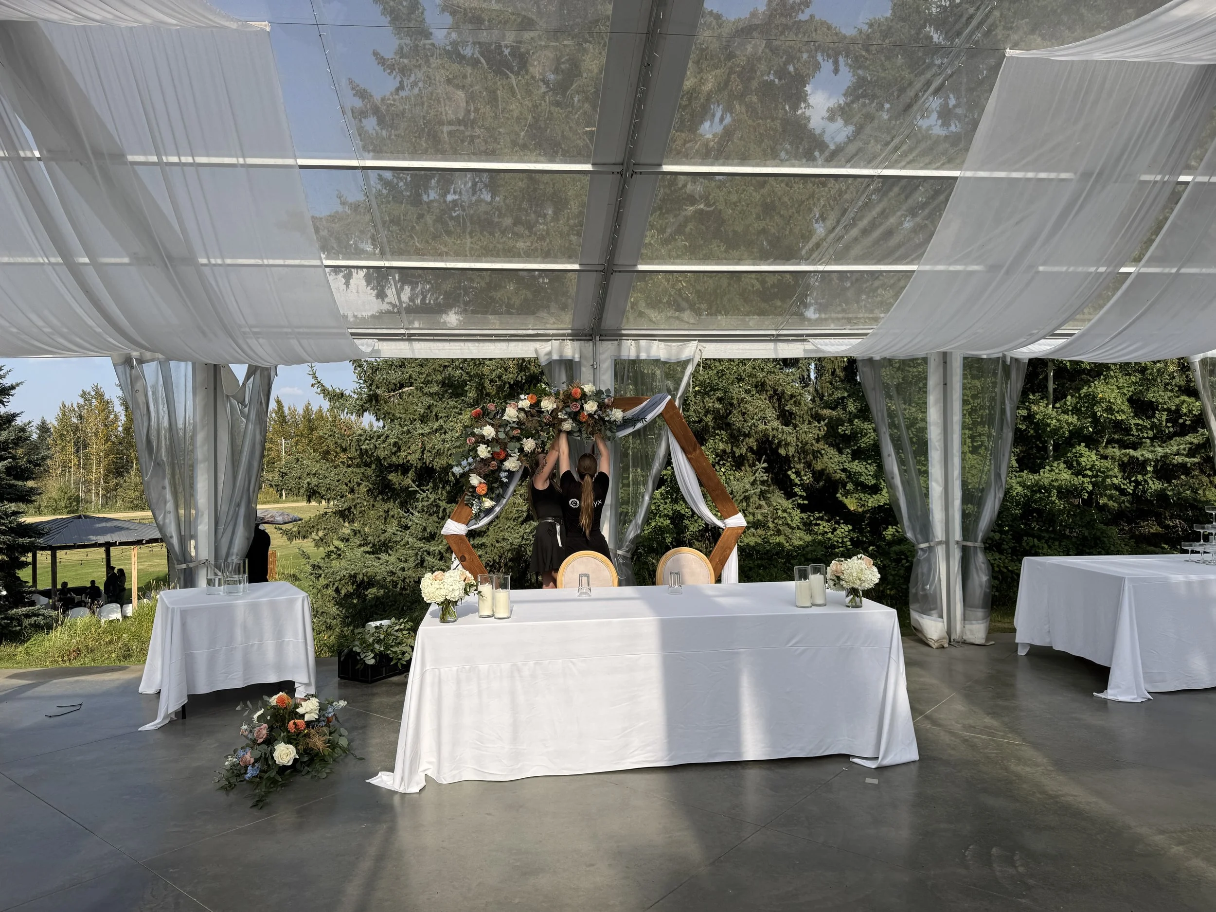Staff prepare décor inside Pine and Pond's clear reception tent, showcasing the planning, coordination, and attention to detail behind every wedding day.