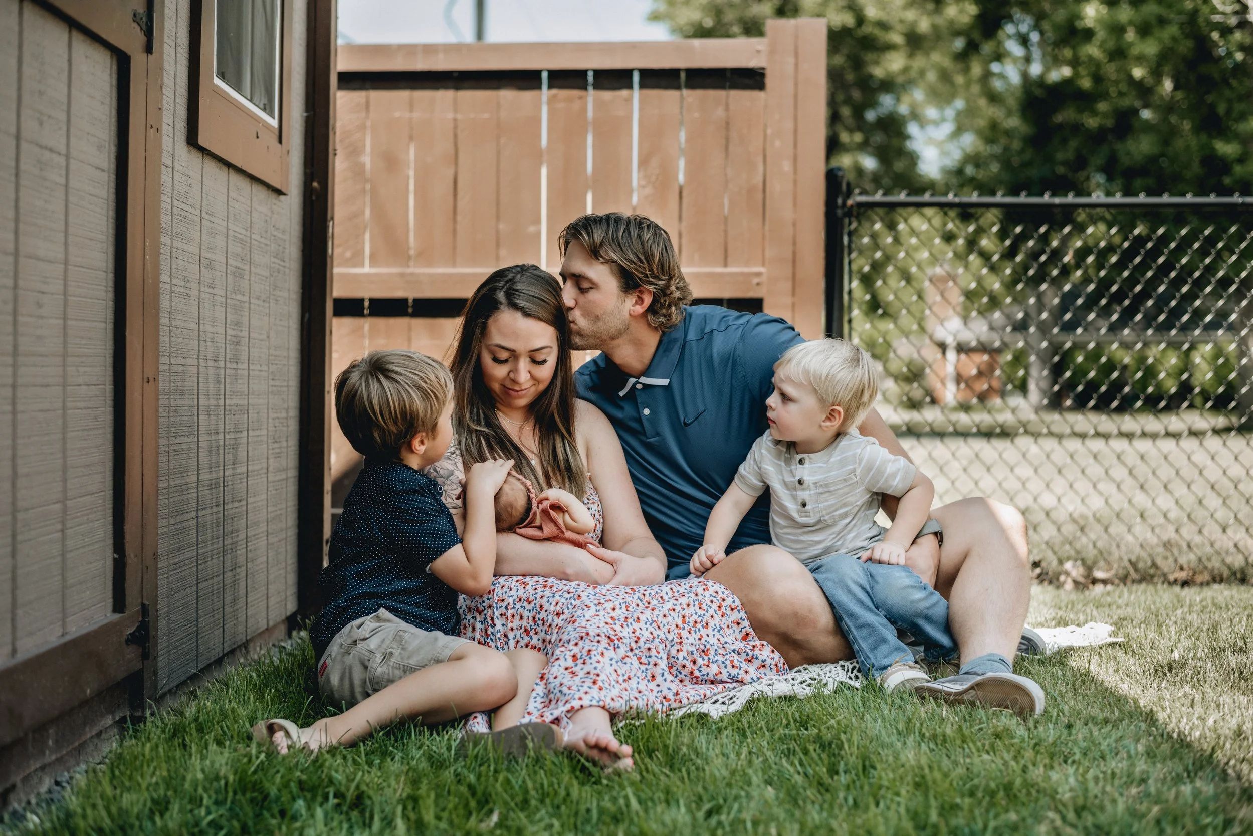 A happy family with their newborn baby sitting outside in their backyard at Elida, Ohio.