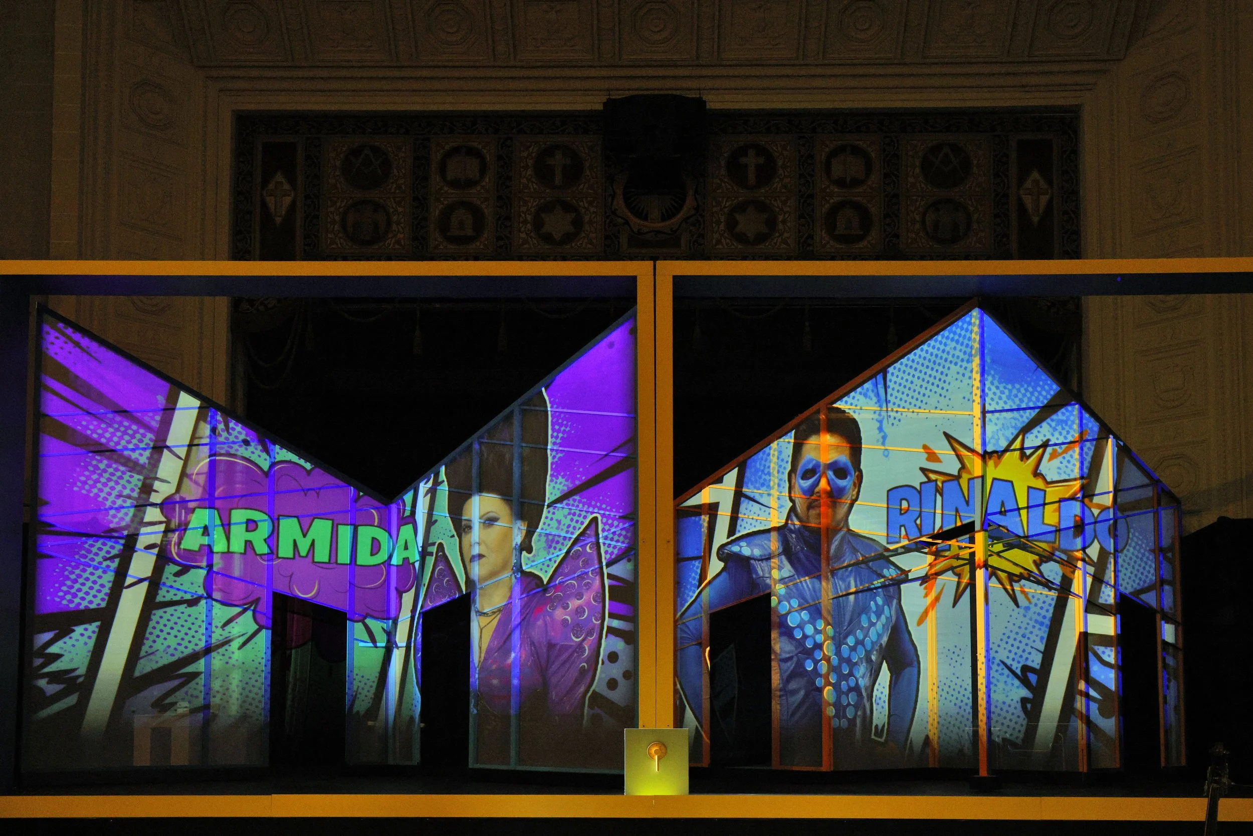 Colorful comic-style promotional display for an event called 'Armida Final,' featuring two characters, one looking serious and the other with a skull mask, with vibrant graphics and speech bubbles.