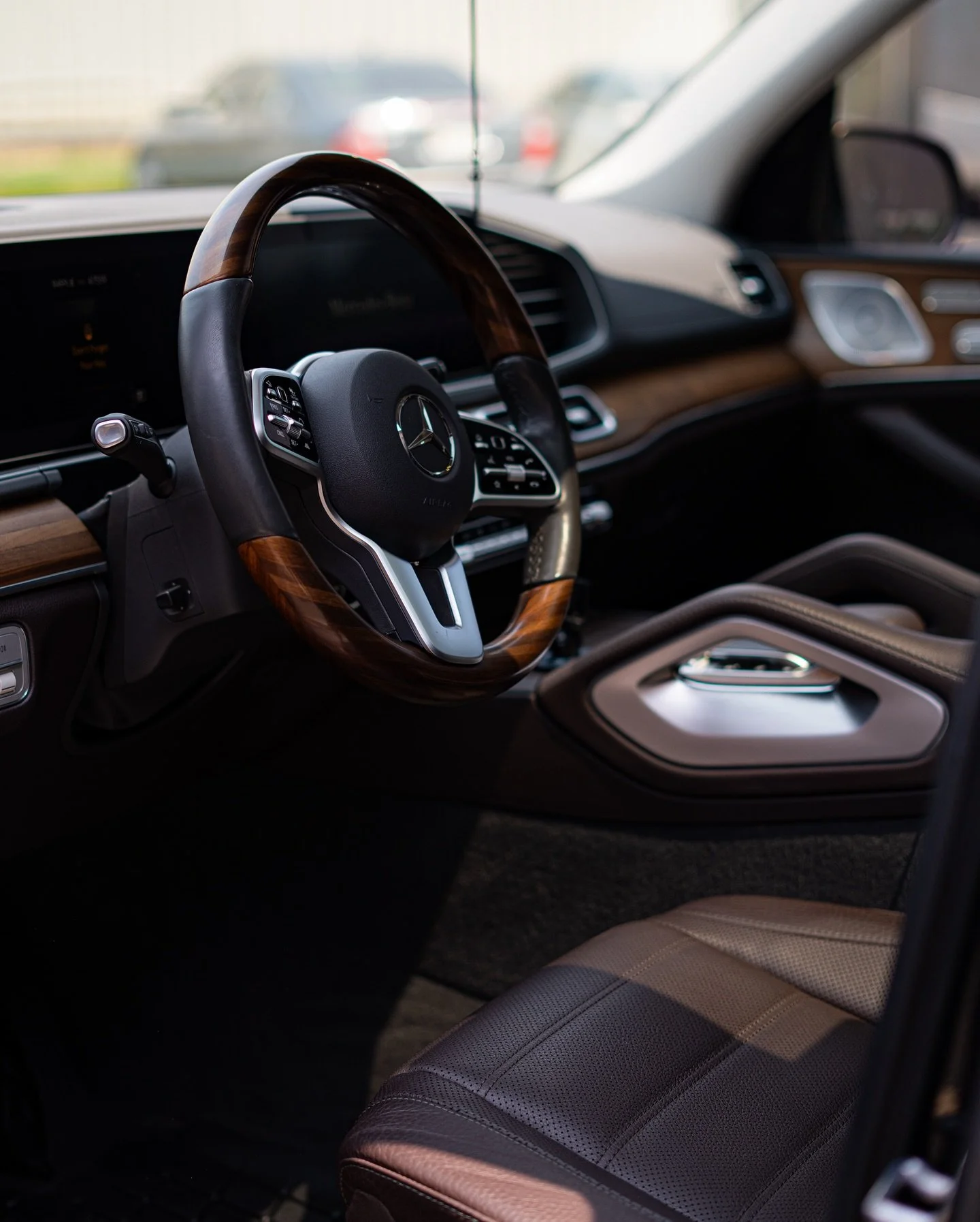 Interior of a luxury Mercedes-Benz vehicle with a wooden steering wheel, digital dashboard, and leather seats.