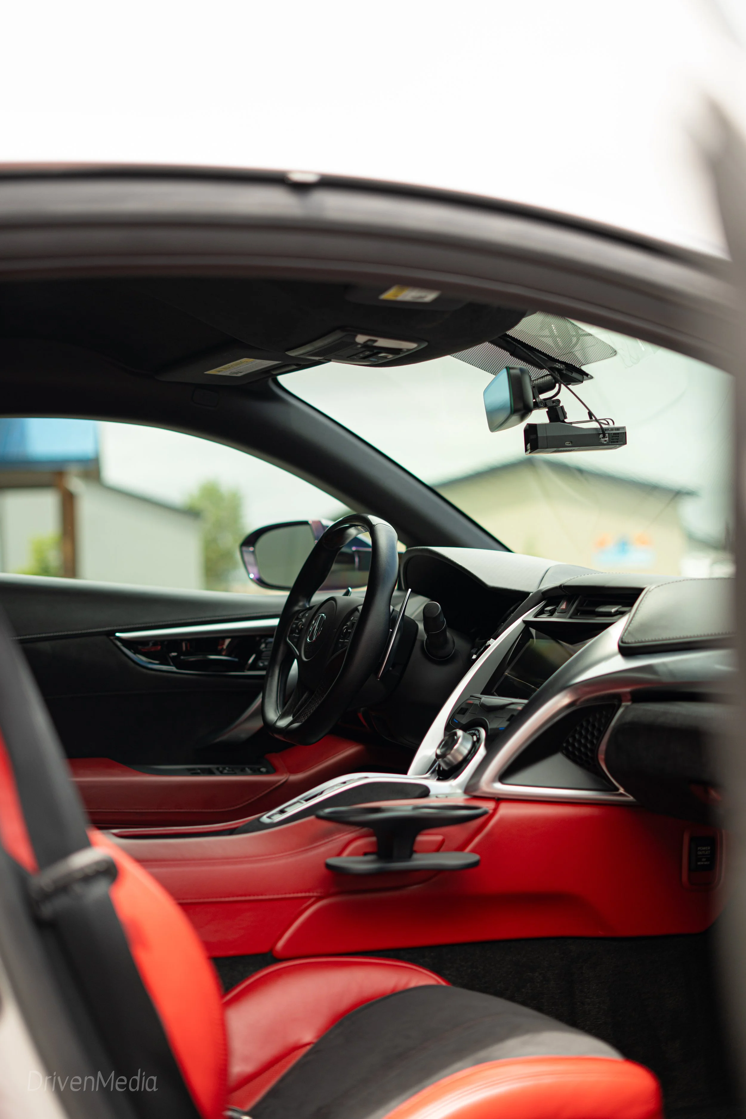 Interior of a car showing front seats, steering wheel, dashboard, and mounted dashcam.