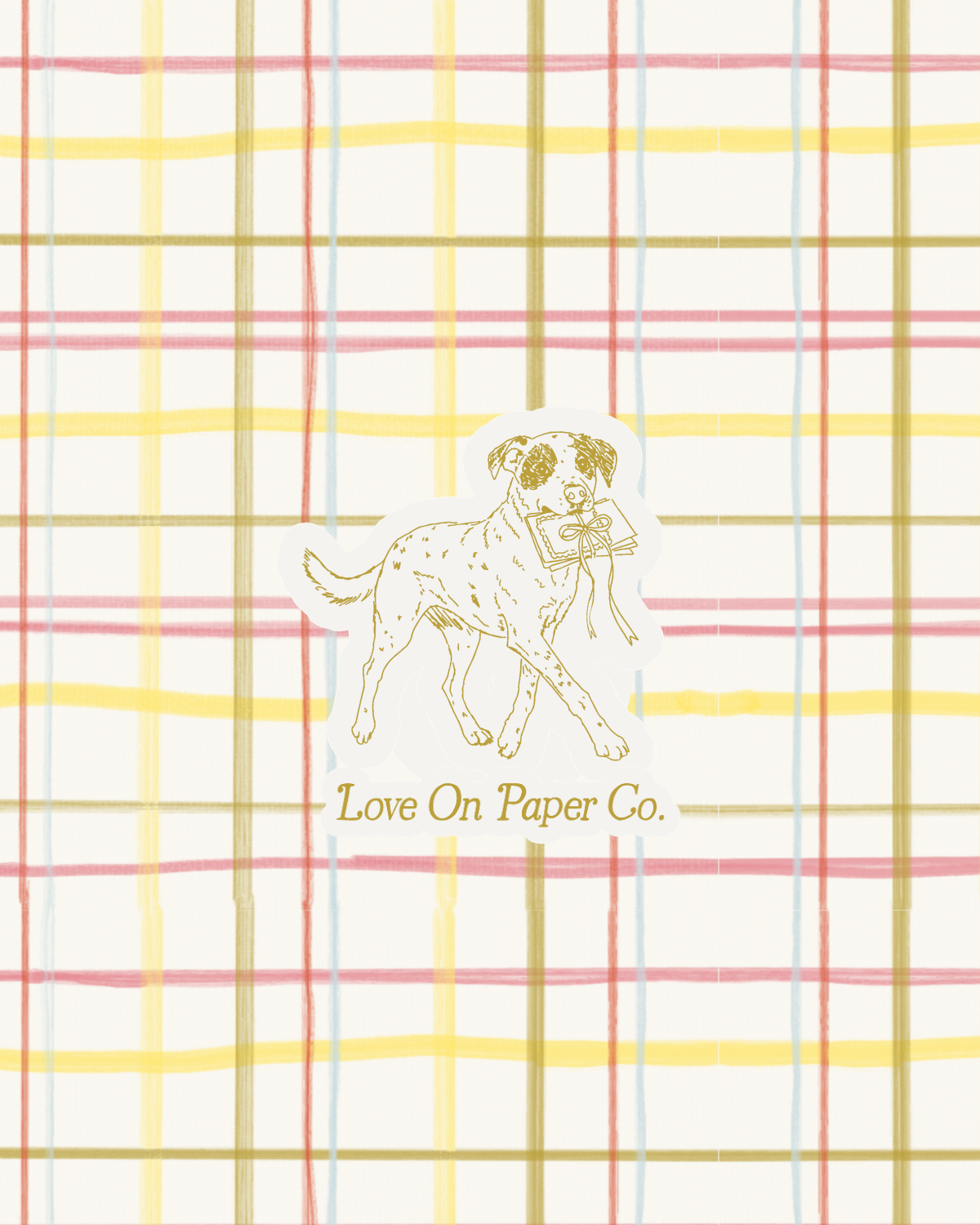 A sticker of a dog carrying a gift, with the text "Love On Paper Co." below, placed on a background of plaid paper with red, yellow, blue, and beige lines.