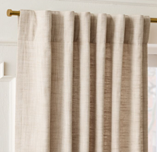 Beige curtains hanging on a gold curtain rod.