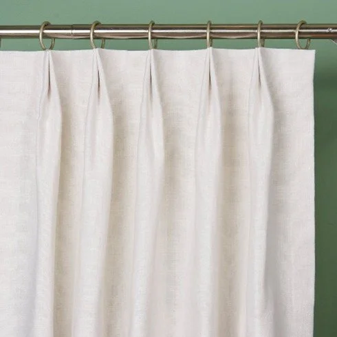 White shower curtain hanging on a curtain rod against a green wall.