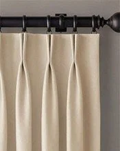 Beige curtains hanging on a black curtain rod with decorative finial