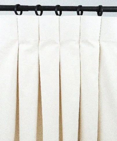 Cream-colored curtains hanging from a black curtain rod