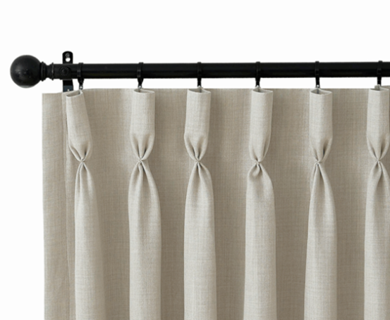 Cream-colored curtains hanging from a black curtain rod with decorative finials.