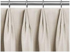 A row of beige curtains hanging from a metal curtain rod