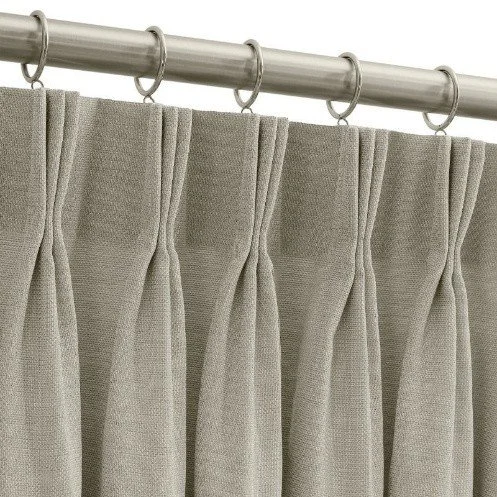 A beige fabric curtain hanging from a metal rod with rings.