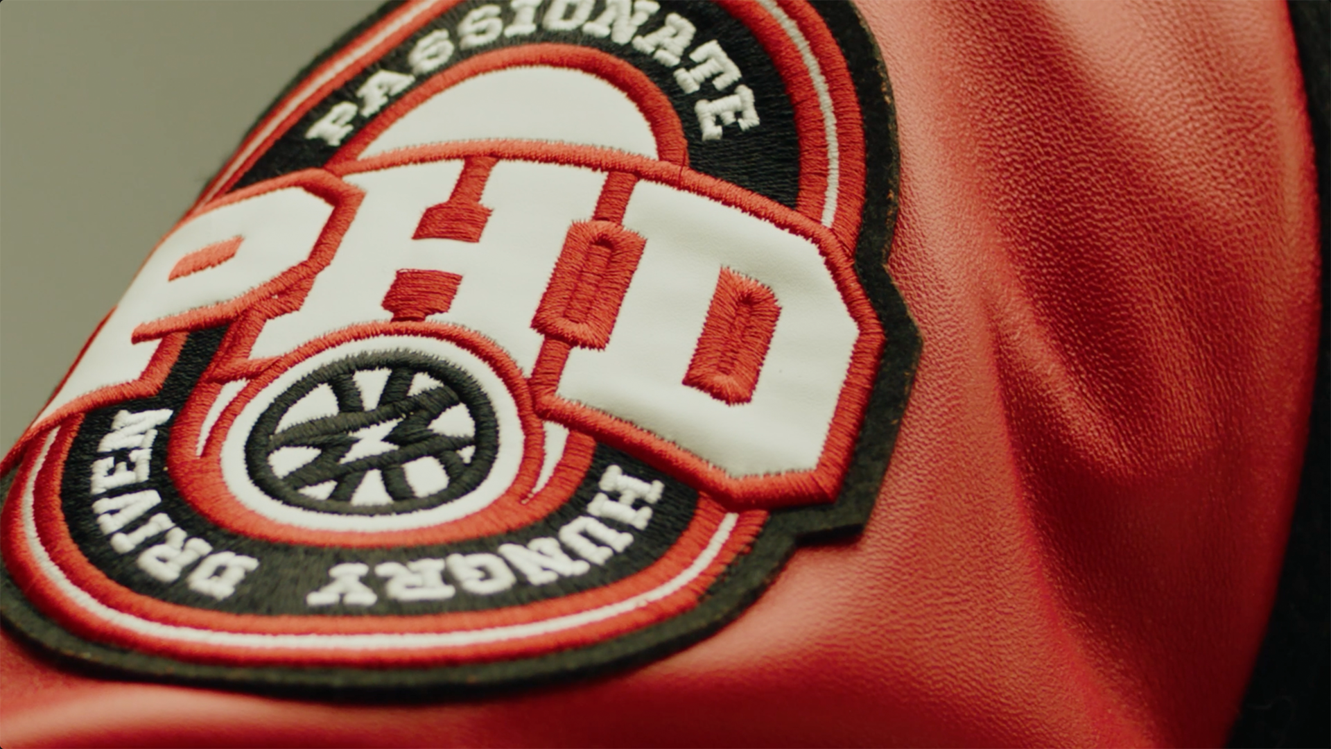 Close-up of a firefighter badge embroidered on a red jacket, with a black, white, and red design.