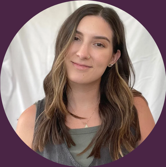 Young woman with long brown hair, wearing a nose ring and small earrings, smiling with a slight tilt of her head, wearing a gray sleeveless top, against a white and purple background.